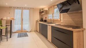 A modern kitchen with a wooden countertop, a built-in oven, and a window with curtains.