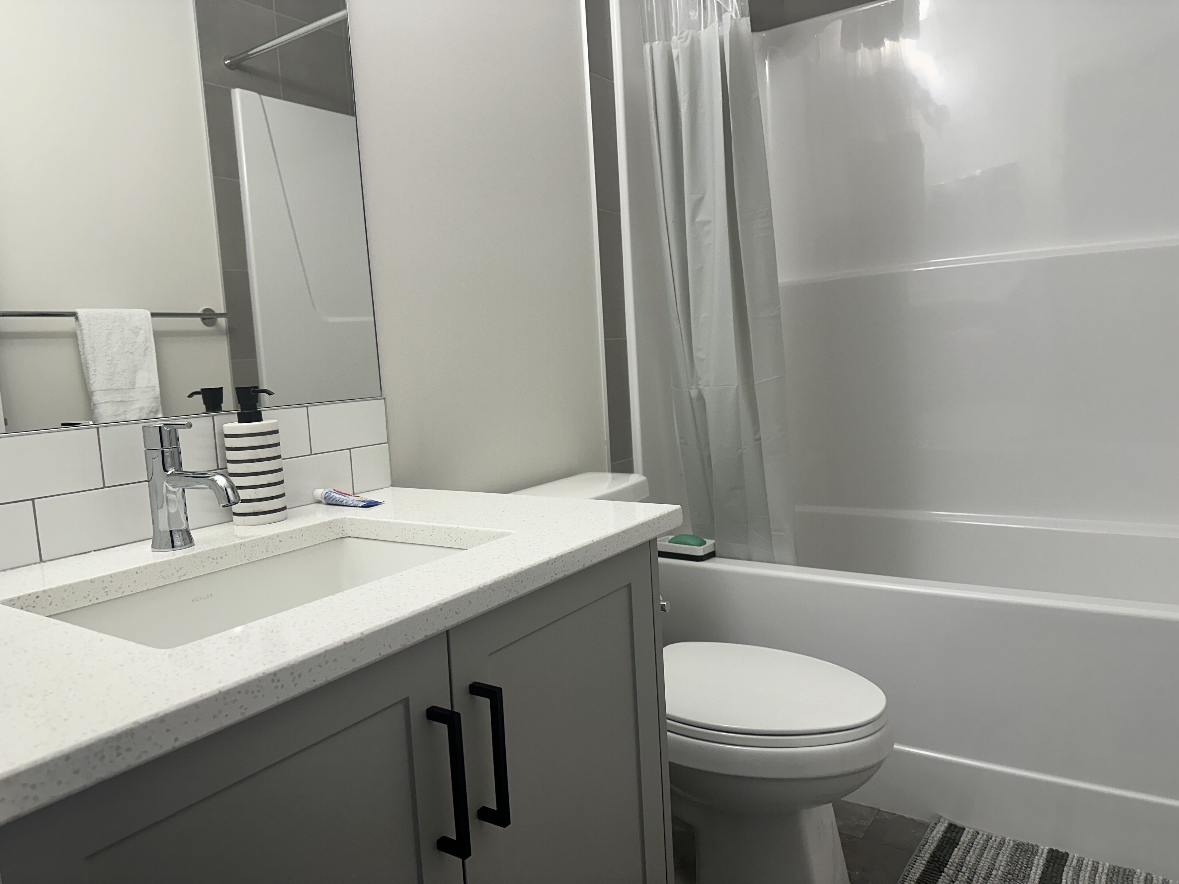 A bathroom with a white sink, a mirror, a toilet, and a shower curtain.