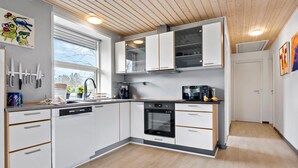 A modern kitchen with white cabinetry, a built-in oven, and a microwave. There is a window with a view of trees outside. - 3 bedroom stunning home in Fårvang (Fårvang)