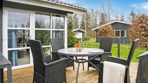An outdoor patio with wicker furniture, a glass table, and a view of the surrounding area including a house and trees. - 3 bedroom stunning home in Fårvang (Fårvang)