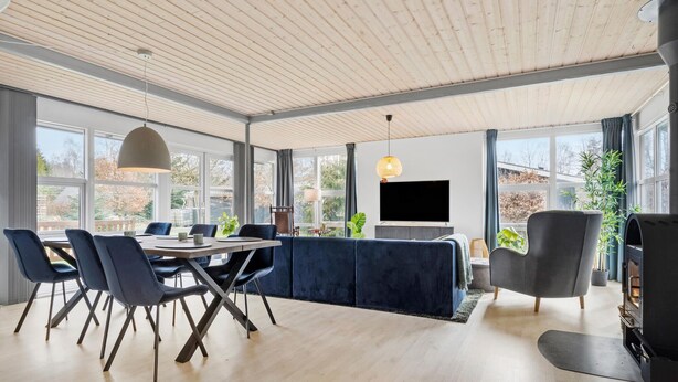 A modern living room with a dining area, large windows, and a fireplace. - 3 bedroom stunning home in Fårvang (Fårvang)