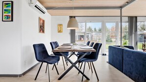 A modern dining area with a wooden table, blue chairs, and a large window offering a view of the outdoors. - 3 bedroom stunning home in Fårvang (Fårvang)