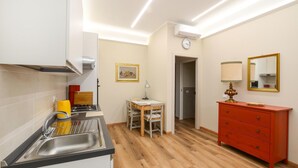 A compact kitchen with a sink, stove, and a small dining table with chairs. There's a red dresser with a mirror and a lamp. - Awesome apartment in Camaiore with WiFi (Camaiore)