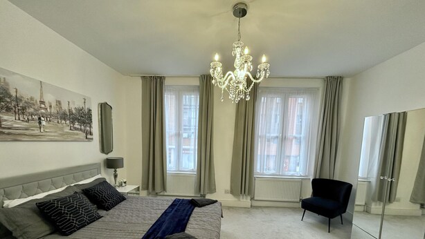 Een slaapkamer met een groot bed, een kroonluchter, een stoel en een kledingkast.