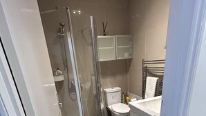 Een moderne badkamer met een douchecabine van glas, een toilet en een wastafel.