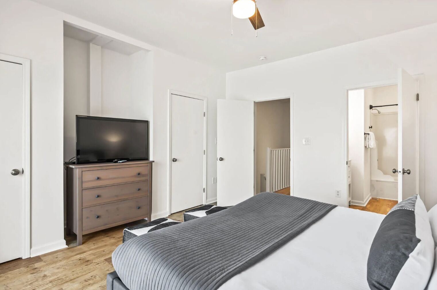 Un dormitorio moderno con cama, cómoda y televisor.