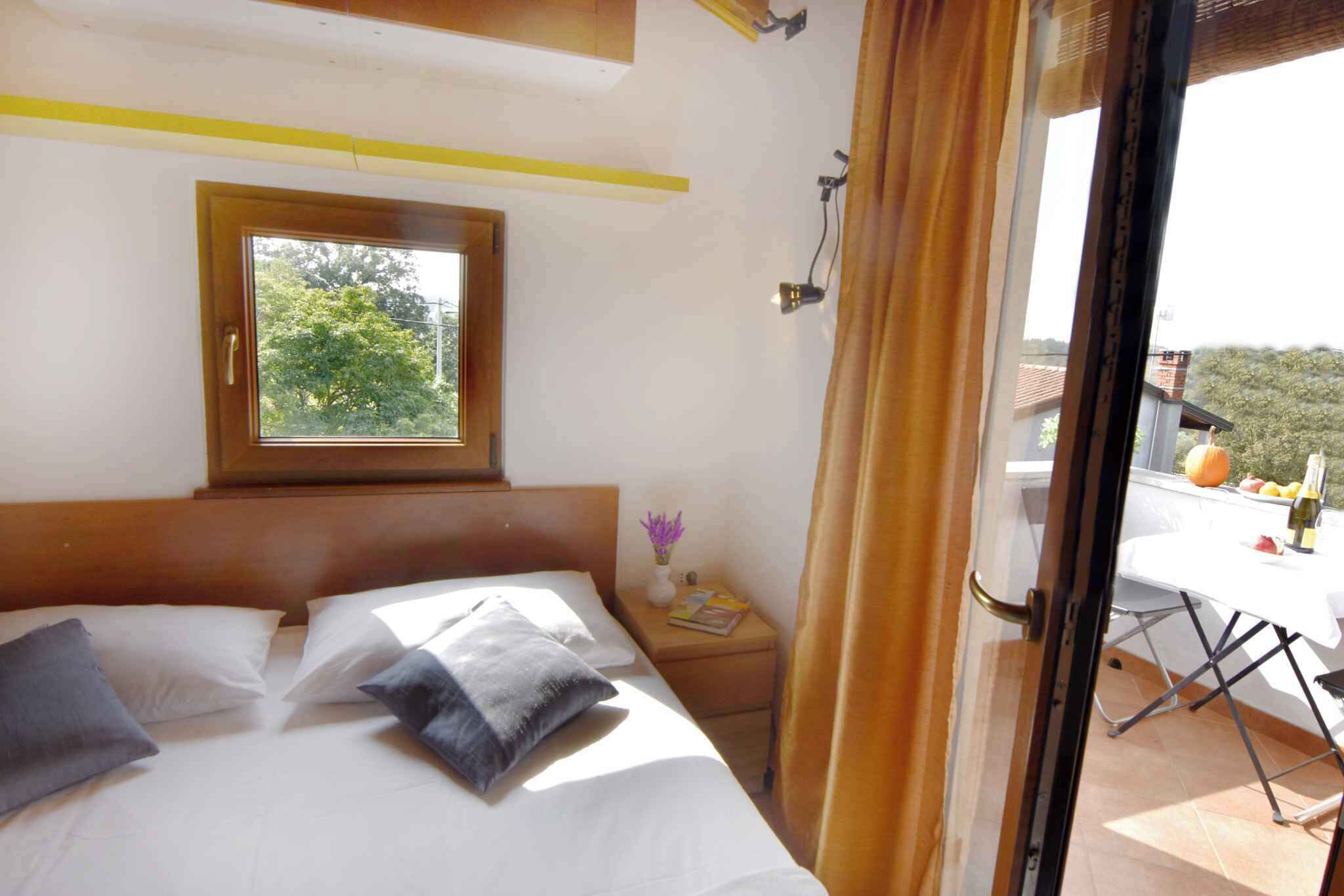 A bedroom with a bed, a nightstand, a window, and a view of the outdoors.
