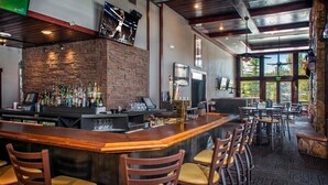 A bar area with a brick wall, wooden bar counter, and multiple bar stools.