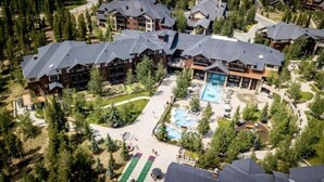 An aerial view of a resort with multiple buildings, a central pool area, and surrounding greenery.