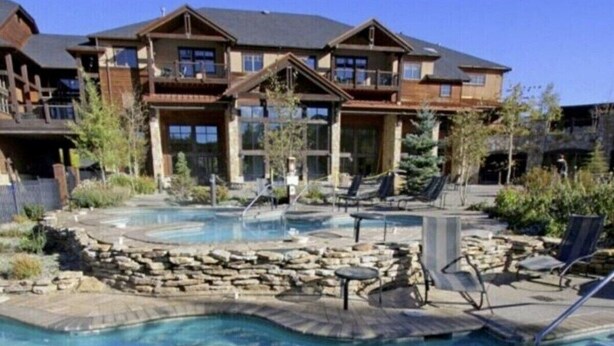 A resort with a large pool area, multiple balconies, and a stone retaining wall.