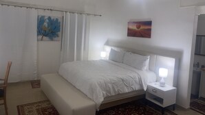 A bedroom with a bed, nightstands, a ceiling fan, and a painting on the wall.