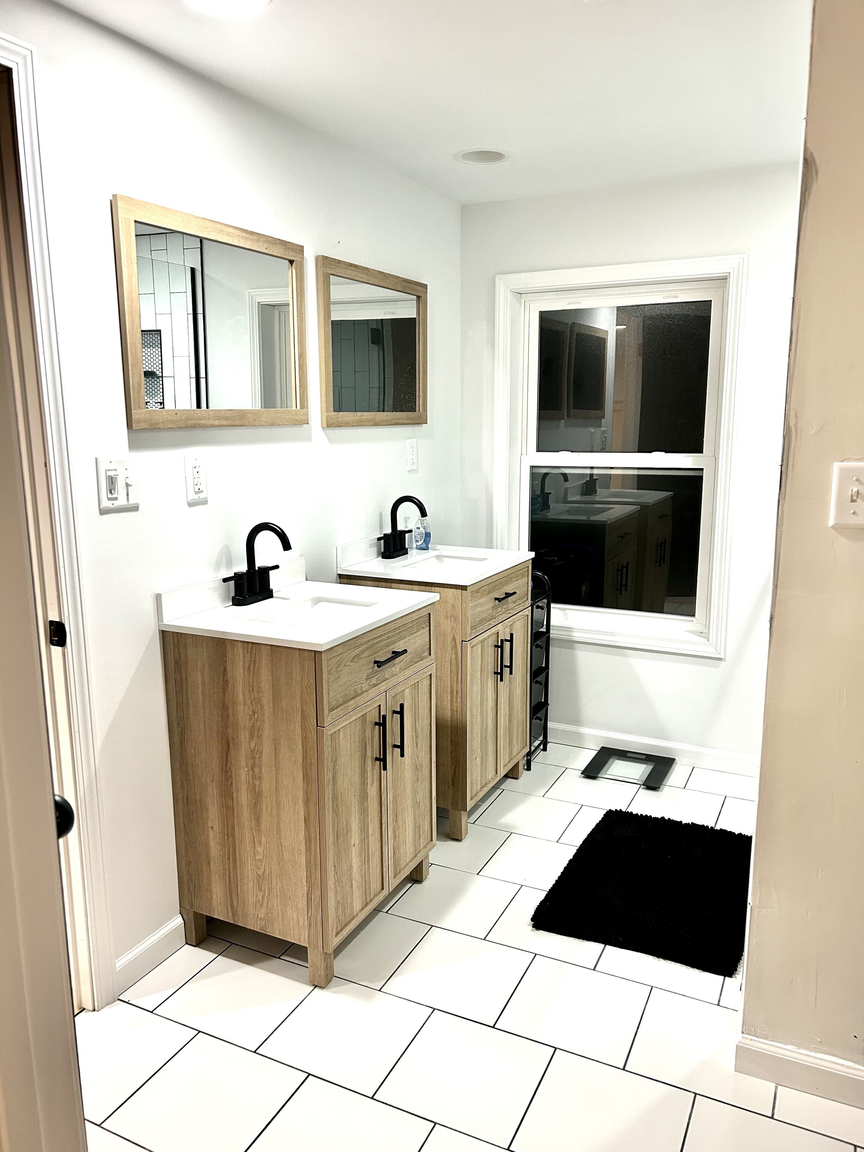 Un baño moderno con dos lavamanos, muebles de madera y un ventanal amplio.