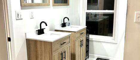 Un baño moderno con dos lavamanos, muebles de madera y un ventanal amplio.