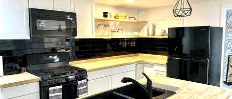A modern kitchen with black appliances, white cabinets, and wooden countertops.