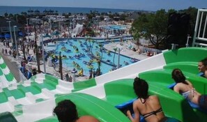 Un parc aquatique doté de plusieurs piscines et de toboggans, entouré de bâtiments et de palmiers.