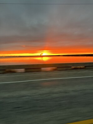 A sunset over a body of water with a road in the foreground. - Fun Crab Shack ~ 4 bedrm ~ 1 Block from Water (Rockport)