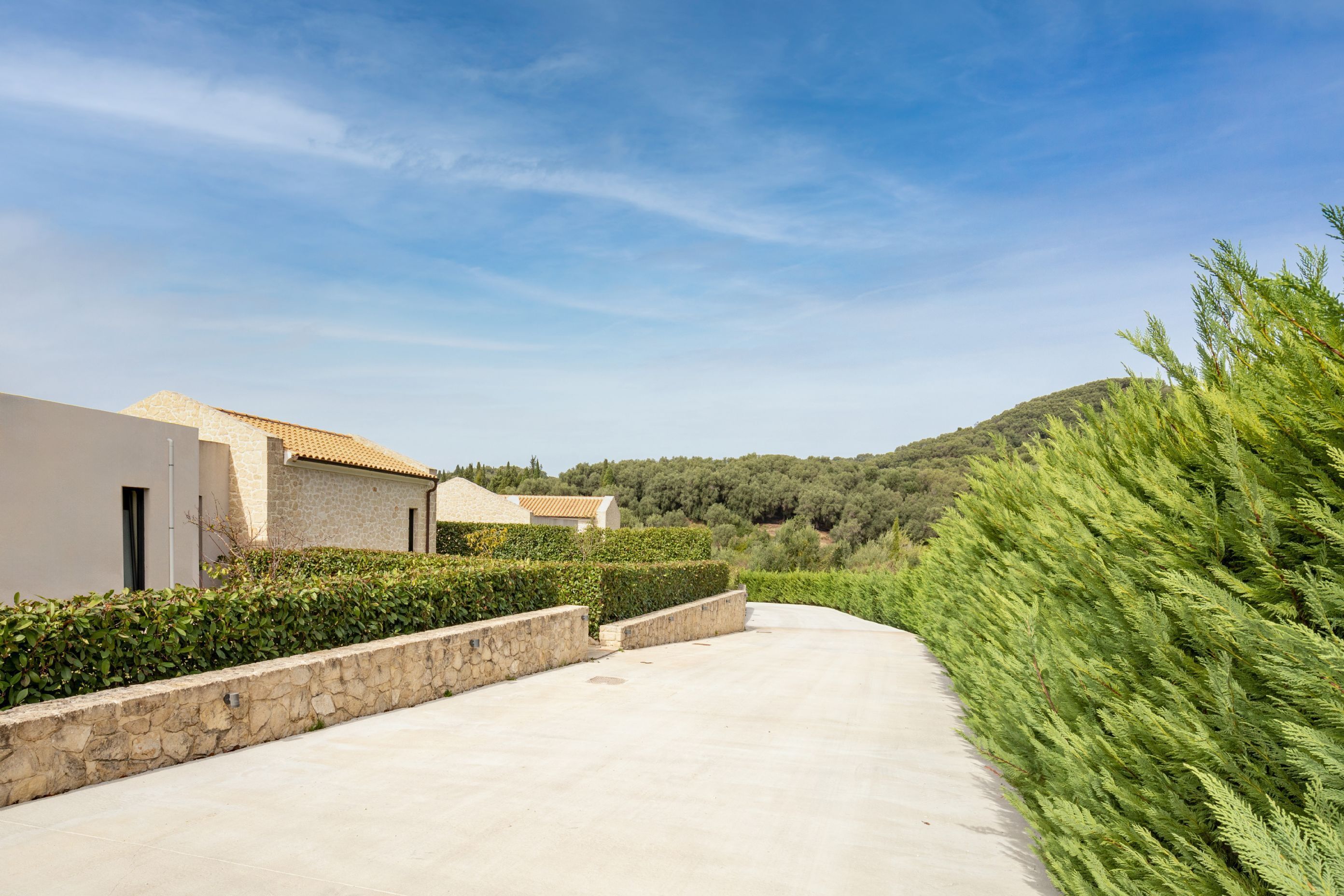 A paved pathway leading to a building with a stone facade and a tiled roof.