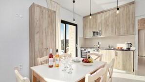 A modern kitchen with wooden cabinets, a dining table with chairs, and a view of the outdoors. - Indulge in Opulence at Lithari Enac—Luxury Villa with Private Pool (Kavvadades)