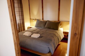 A neatly made bed with a grey duvet, two pillows, and two folded towels. - Porpoise Palace - Huskisson (Huskisson)