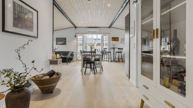 A spacious room with a high ceiling, a dining area with chairs and a table, and a large cabinet with glass doors. - 3 bedroom amazing home in Vejby (Vejby)