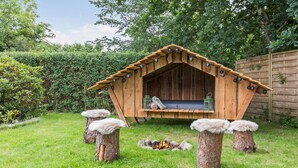A rustic wooden cabin with a sloped roof, a bench inside, and a fire pit in front. - 3 bedroom amazing home in Vejby (Vejby)
