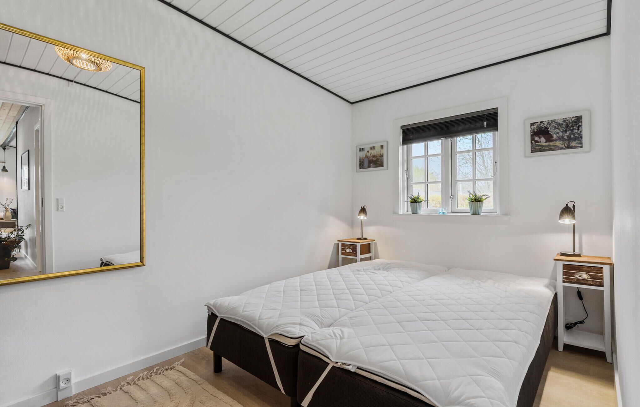 A bedroom with a bed, bedside tables, a window, and a mirror.