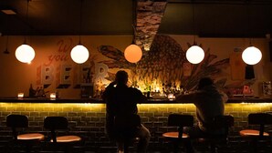 Eine Bar mit Backsteinwand, hängenden Lampen und einem Wandgemälde mit dem Wort "BEER".