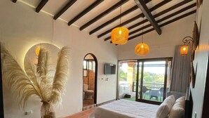 A bedroom with a bed, a large vase with feathers, and two hanging lamps. - Hotel Ecoluxe (El Peñol)