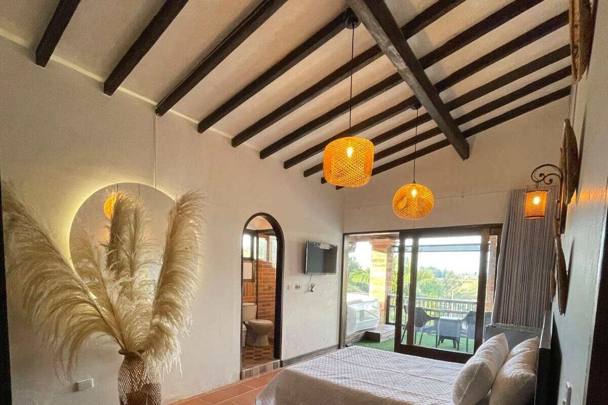 A bedroom with a bed, a large vase with feathers, and two hanging lamps.