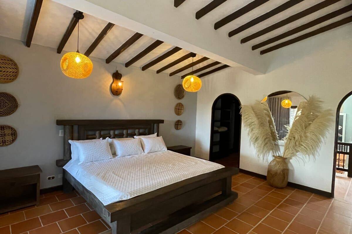 A bedroom with a wooden bed, a large window, and a view of the outside.
