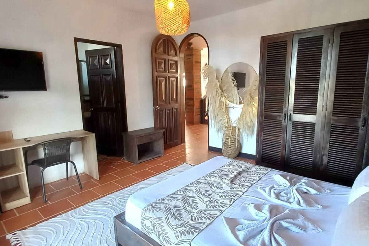 A hotel room with a bed, a desk, a television, and a wardrobe.