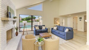 A spacious living room with a fireplace, two sofas, a coffee table, and a large window overlooking a pool. - {On IMG Golf Course! WAFFLE BAR/Pool/GameRoom/Beach Gear++ (Bradenton)