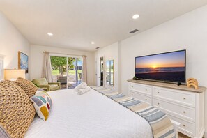 Une chambre d’hôtel équipée d’un lit, d’une télévision, offrant une vue sur l’extérieur et donnant sur un balcon par une porte coulissante.
