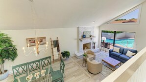 A spacious living area with a fireplace, a pool view, and a dining area with a green table and chairs. - {On IMG Golf Course! WAFFLE BAR/Pool/GameRoom/Beach Gear++ (Bradenton)