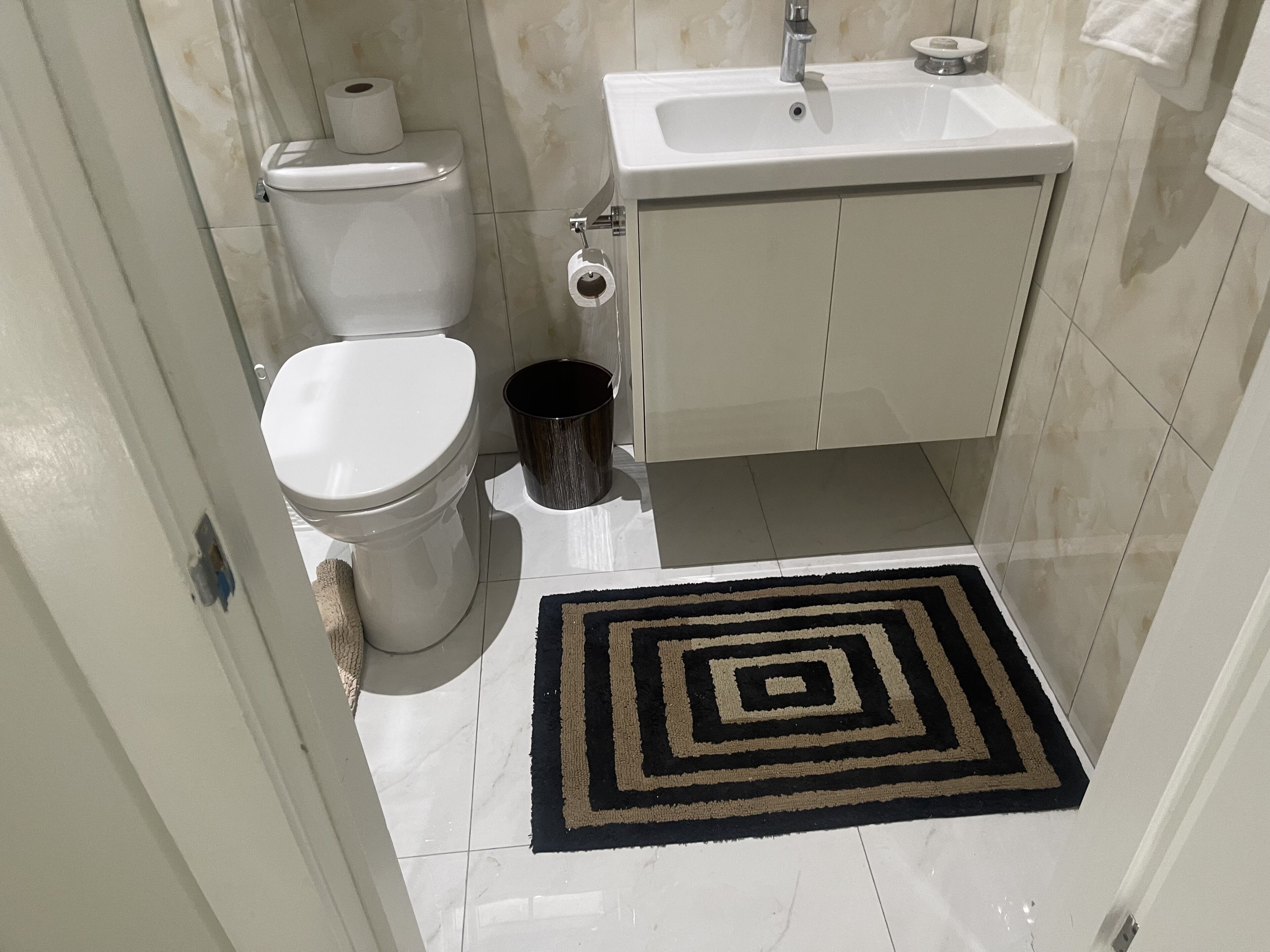 Une petite salle de bain avec des toilettes, un lavabo et une poubelle.