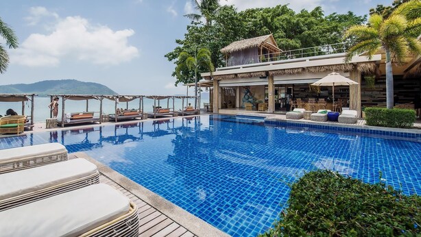 A pool area with lounge chairs and umbrellas, a bar, and a view of the sea. - Malee Resort Studio 858 (Rawai)