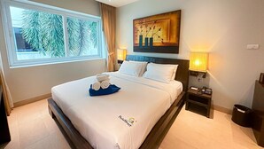 A hotel room with a large bed, a window with a view of palm trees, a painting on the wall, and a bedside lamp. - Malee Resort Studio 858 (Rawai)