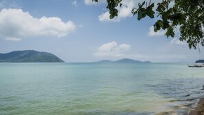 A calm sea with boats on the right, a beach on the right, and mountains in the background. - Malee Resort Studio 858 (Rawai)