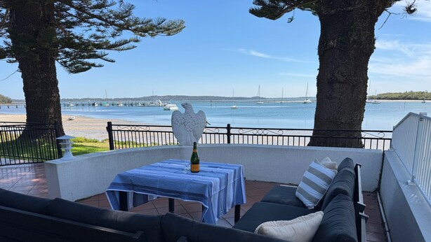 A patio with a table set for two, overlooking a body of water with boats.