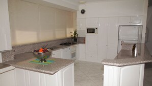 A kitchen with white cabinets, a granite countertop, a microwave, and a sink.