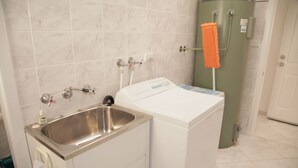 A compact laundry area with a washing machine, a sink, and a towel rack.