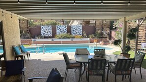 Ein überdachter Außenbereich mit Pool, Sitzgelegenheiten und dekorativen Paneelen.