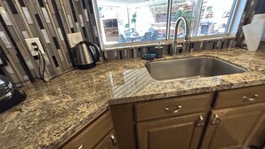 Eine Küche mit Granit Arbeitsplatten, einer Edelstahl-Spüle und Holzschränken.