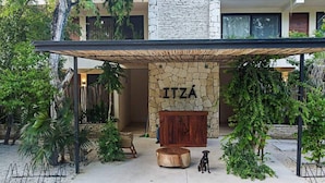 A modern building with a stone facade and a wooden bench labeled "ITZÁ". - Your oasis awaits at our luxury penthouse-100% private rooftop with plunge pool, stunning views, 2 additional shared pools on the ground floor and a building elevator just outside the front door.  FREE extras, backup generator and water softener. (Tulum)