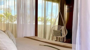 A bedroom with a bed, a hanging chair, and curtains. - Your oasis awaits at our luxury penthouse-100% private rooftop with plunge pool, stunning views, 2 additional shared pools on the ground floor and a building elevator just outside the front door.  FREE extras, backup generator and water softener. (Tulum)
