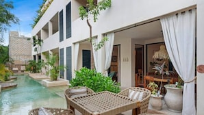 A poolside area with wicker furniture, a dining table, and potted plants. - Your oasis awaits at our luxury penthouse-100% private rooftop with plunge pool, stunning views, 2 additional shared pools on the ground floor and a building elevator just outside the front door.  FREE extras, backup generator and water softener. (Tulum)