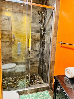 A shower with a glass door, a towel rack, and a tiled floor. - Gîte du monde (Québec City)