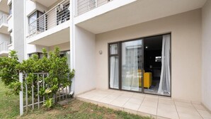 Un apartamento moderno con balcón, grandes puertas correderas de vidrio y un pequeño jardín.
