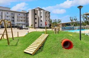 A playground with a wooden slide, a red tunnel, and climbing structures.