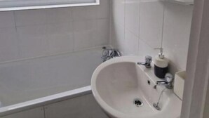 Une salle de bain avec un lavabo blanc, un miroir et un espace douche.